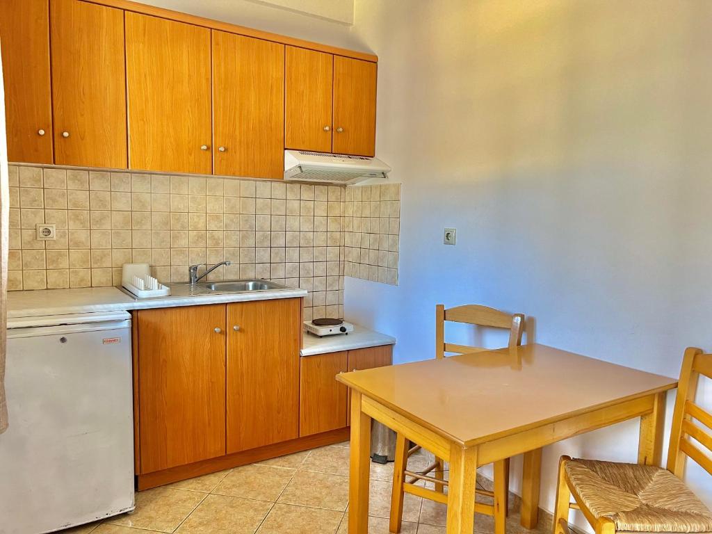 a kitchen with wooden cabinets and a table and a sink at Marinos Studios and Apartments in Gialiskari