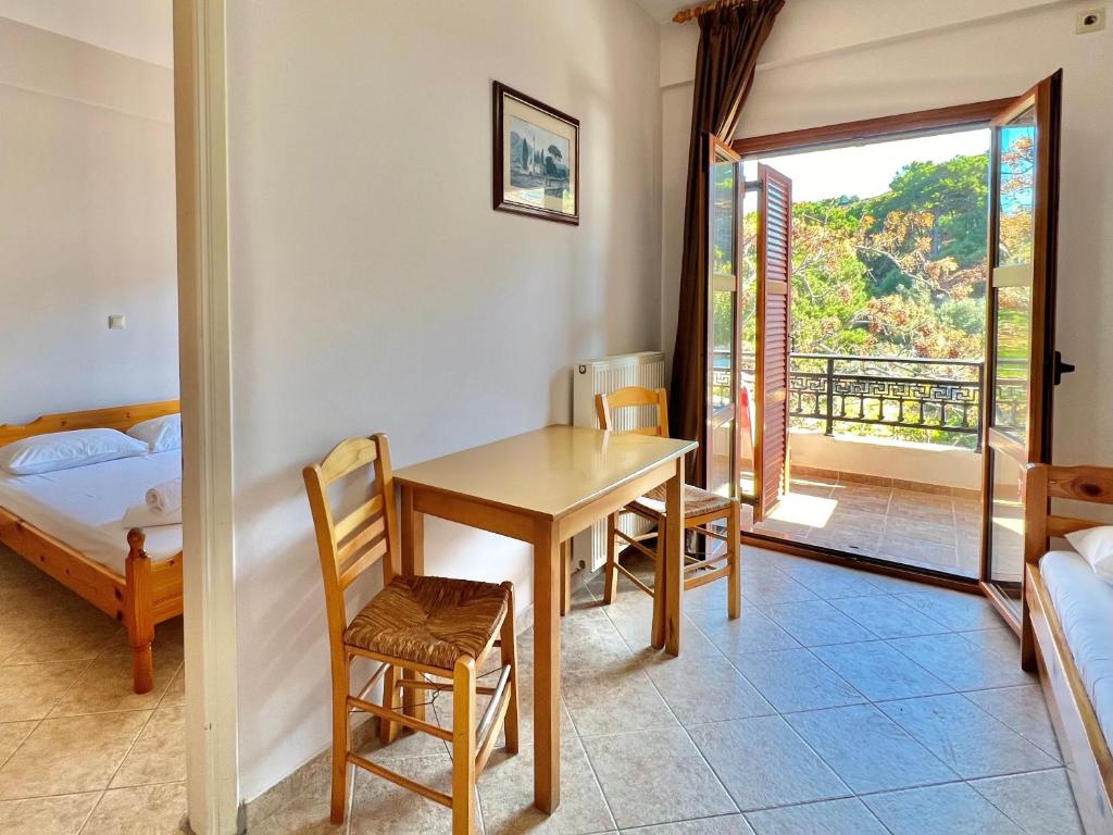 a room with a table and a bed and a window at Marinos Studios and Apartments in Gialiskari