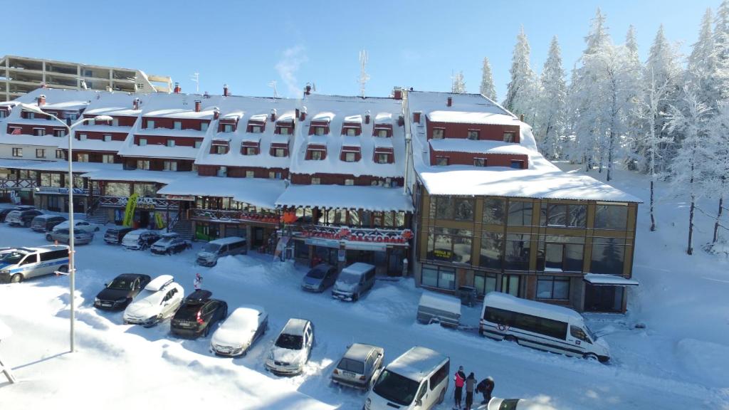 a snow covered building with cars parked in a parking lot at Hotel Dva Javora in Jahorina