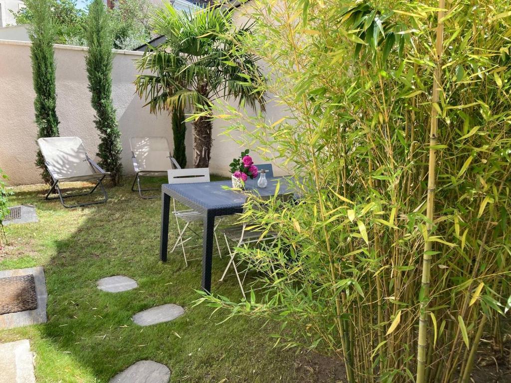 une table noire assise dans l'herbe à côté d'une brousse dans l'établissement La Maison de Léa, à Périgueux