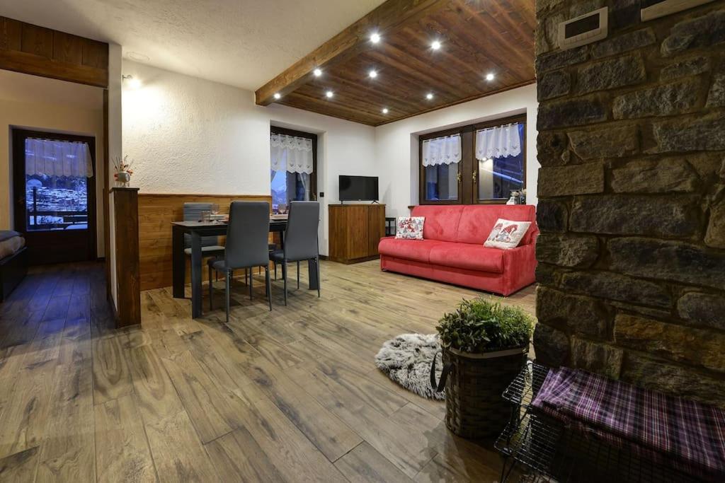 a living room with a red couch and a table at Le Jardin des Montagnes in Morgex