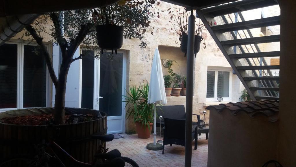 a patio with a tree and a white umbrella at Gîtes Macarien in Saint-Macaire