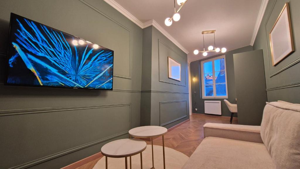 un salon avec un canapé et une télévision au mur dans l'établissement Appartement Le Napoléon Rouen Hypercentre, à Rouen