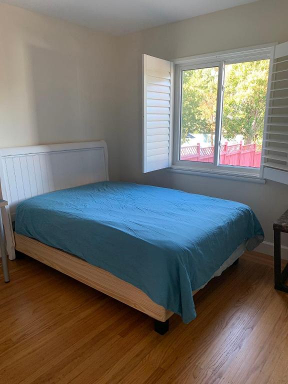 a bedroom with a bed with a blue bedspread and two windows at RoomL in Hayward
