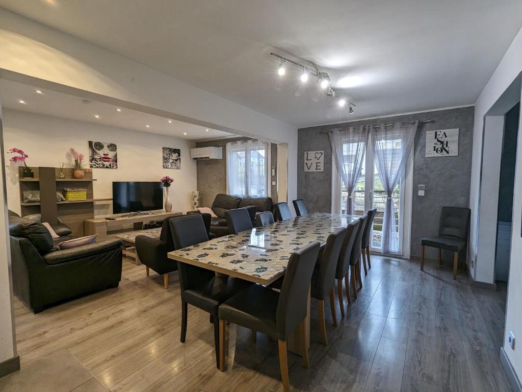 una sala da pranzo e un soggiorno con tavolo e sedie di Chalet spacieux avec sauna, spa et baby-foot, proche stations de ski - FR-1-589-671 a Ramonchamp