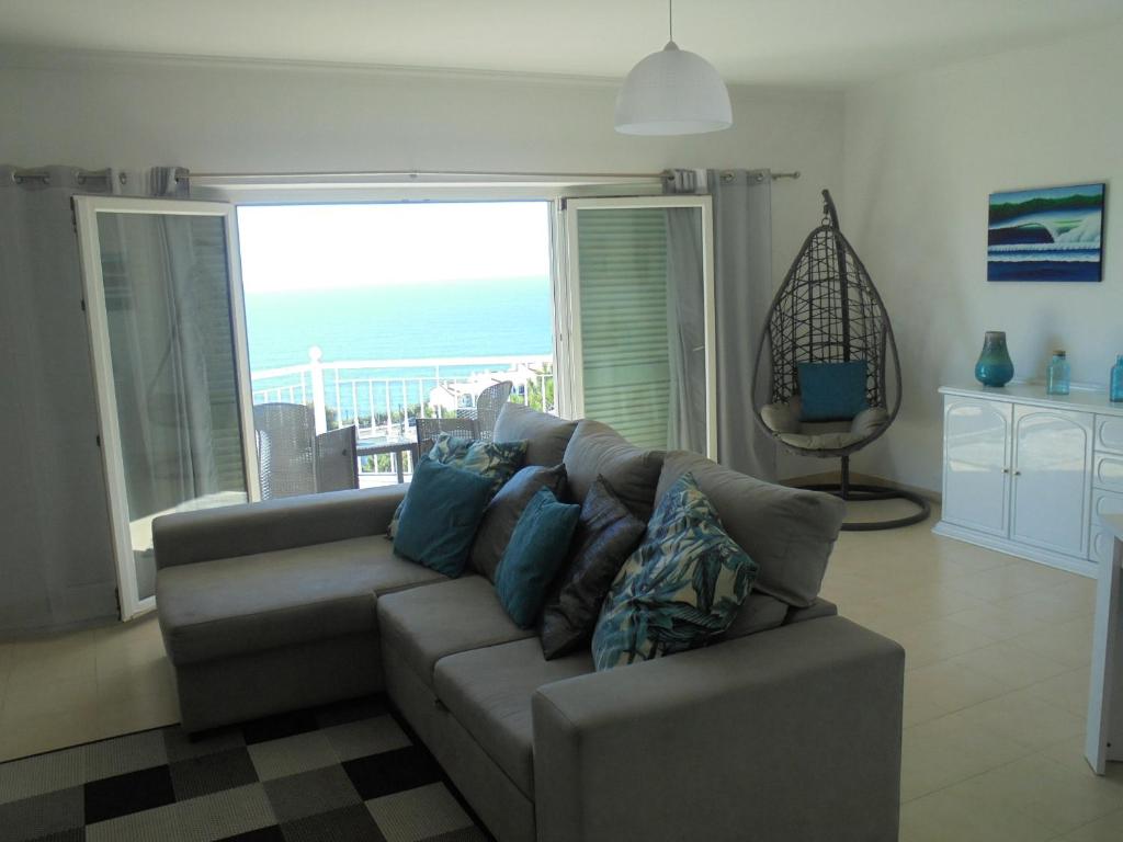a living room with a couch and a view of the ocean at Ericeira Sunset Apartment in Ericeira