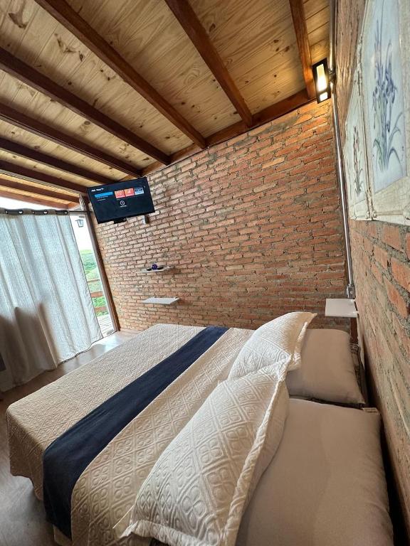 a bedroom with a bed and a brick wall at Chacrinha pousada e restaurante in Caldas