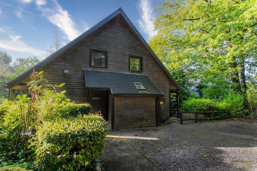 a house with a garage and a gambrel at Weaver, woodland lodge with hot tub for 12 in Oakamoor