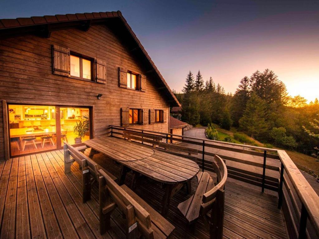 une terrasse en bois avec une table et des bancs en bois dans l'établissement Chalet familial spacieux avec spa, sauna et salle de jeux - FR-1-589-750, à Ban-sur-Meurthe-Clefcy