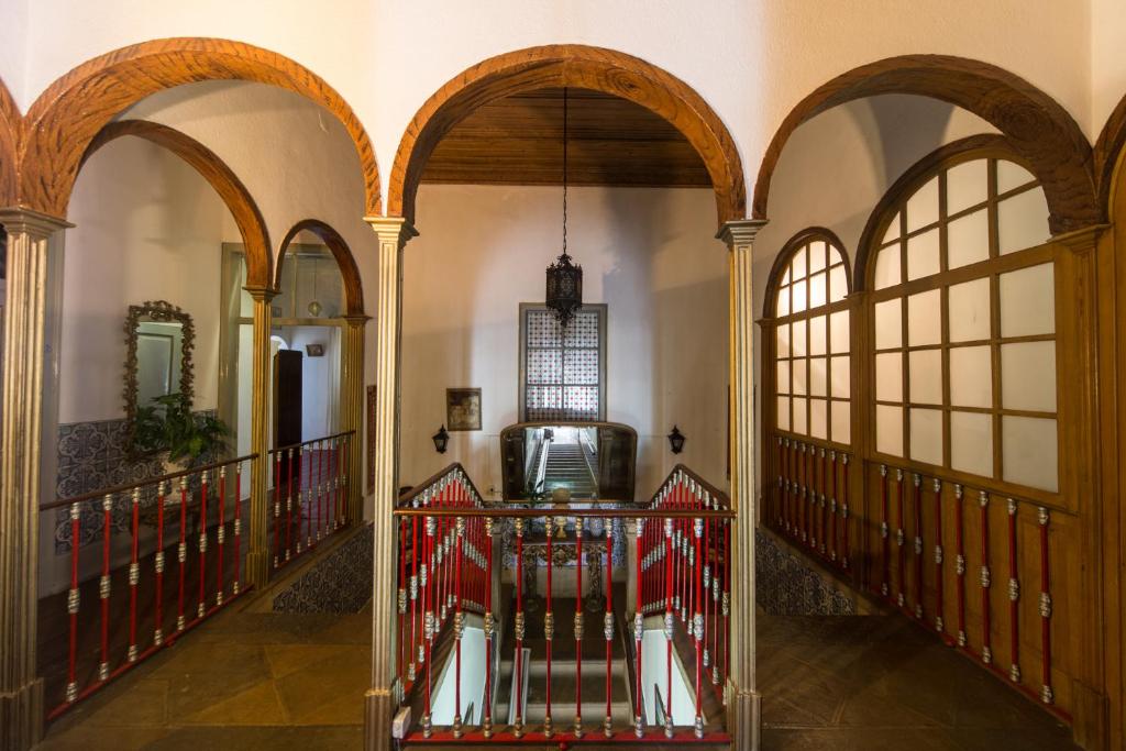 a hallway with arches and a red railing at Hospedaria São Bras in São Brás de Alportel