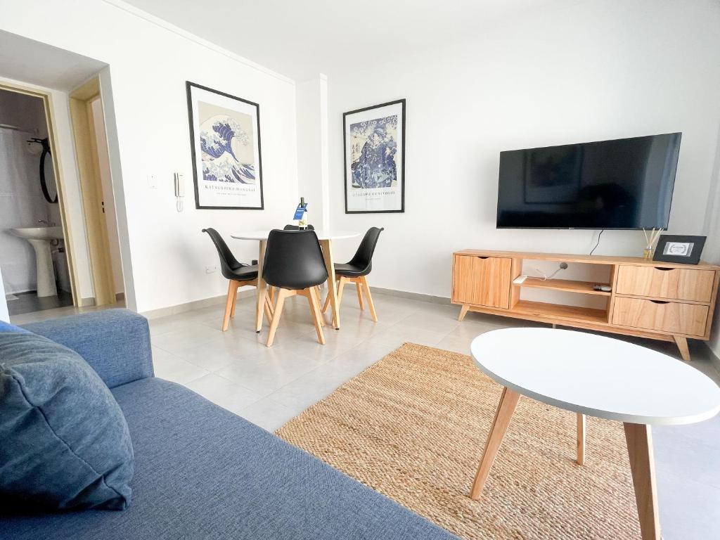 a living room with a couch and a tv and chairs at Saavedra 118 1°H by depptö in Bahía Blanca