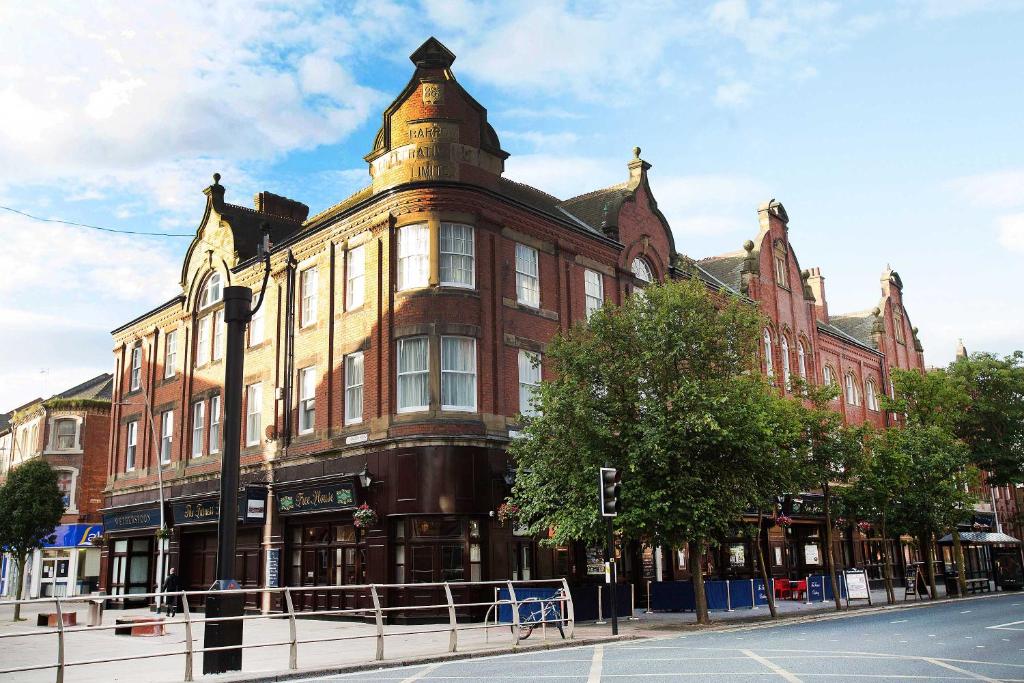 een groot bakstenen gebouw op de hoek van een straat bij The Furness Railway Wetherspoon in Barrow in Furness