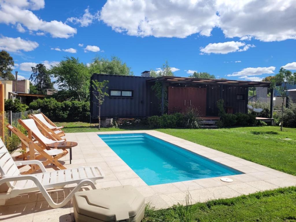 シエラ・デ・ラ・ベンターナにあるPillahuinの椅子と家のある庭のスイミングプール