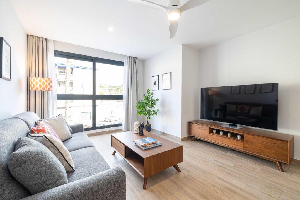 a living room with a couch and a flat screen tv at Beach and golf at modern apartment in Caleta De Velez