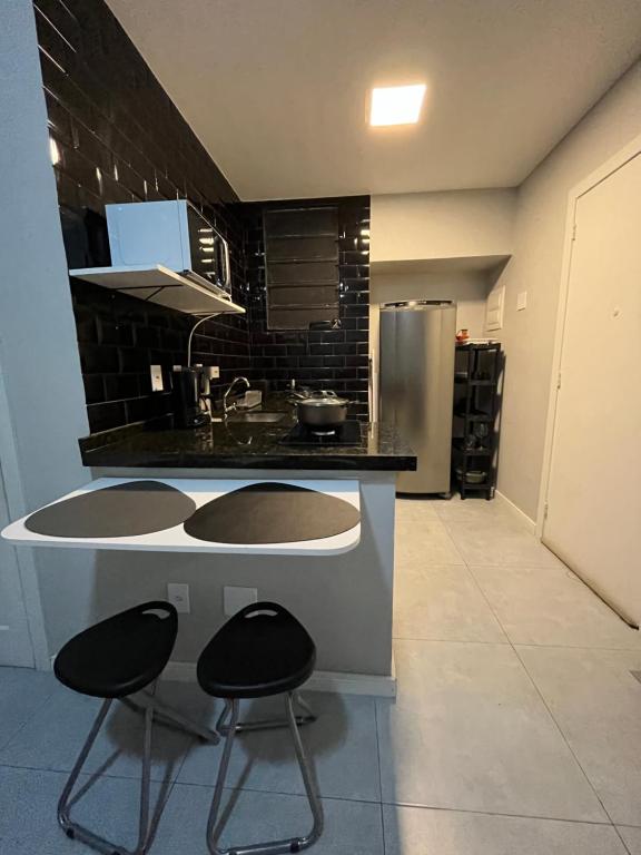 eine Küche mit zwei Hockern und einer Theke mit einem Kühlschrank in der Unterkunft Loft Icaraí in Niterói