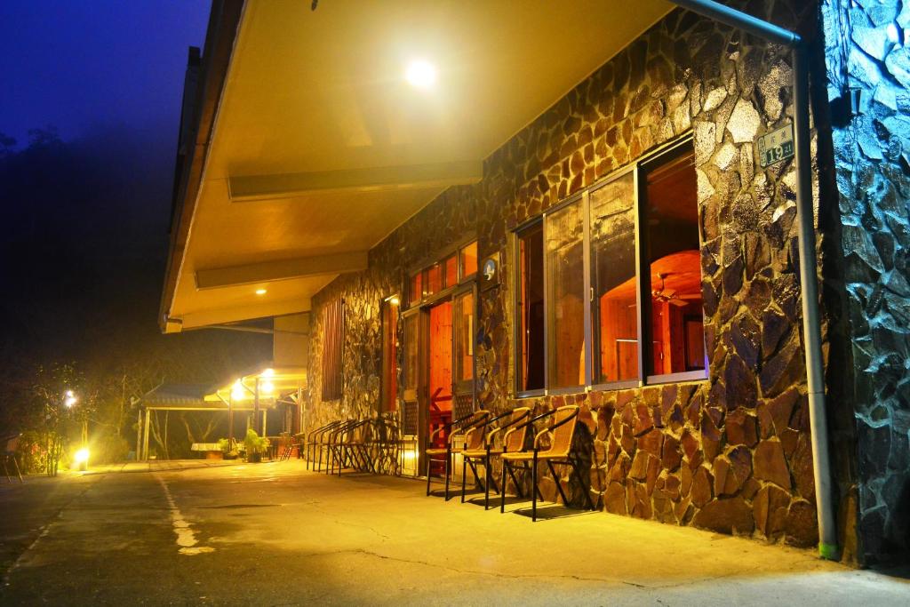 a stone building with chairs outside at night at Zhong Ming Ju Taoyi Fang in Fanlu