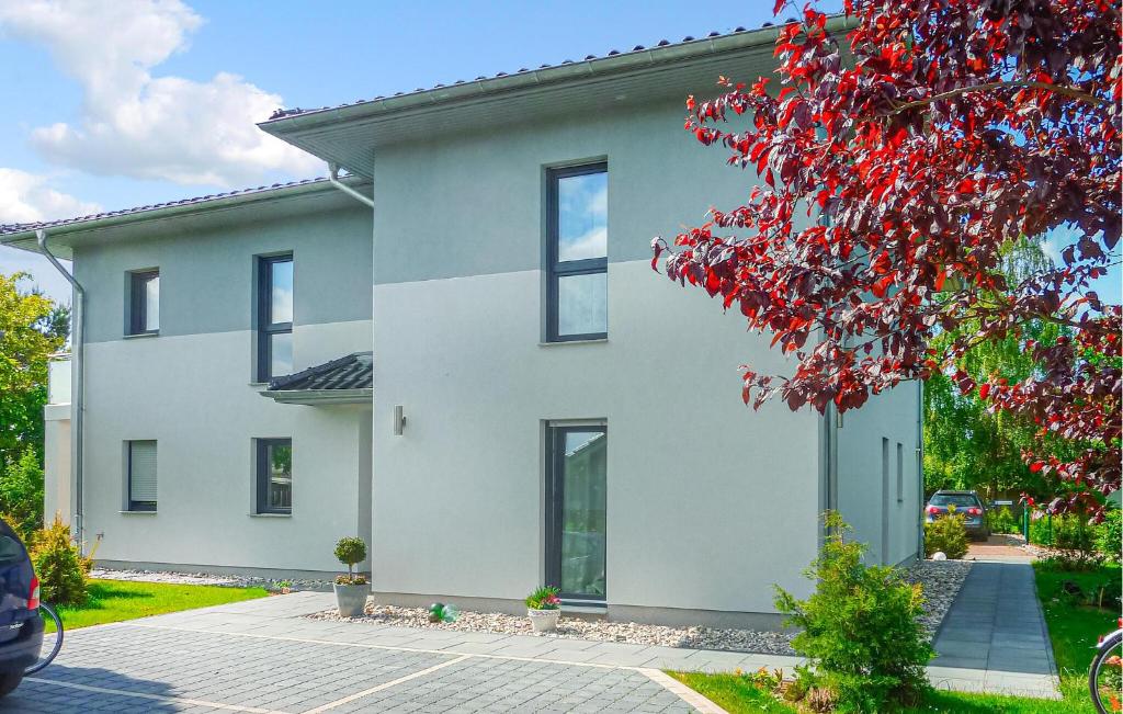 a white house with a red tree in front of it at Ferienwohnung Karlshagen in Ostseebad Karlshagen