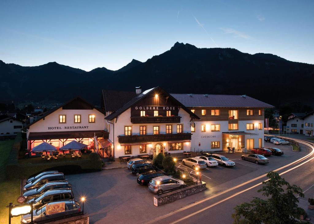 a large building with cars parked in a parking lot at Hotel Goldene Rose in Reutte
