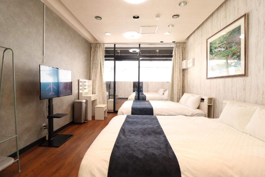 a hotel room with two beds and a flat screen tv at Ideal Momodani イデアール桃谷 in Osaka