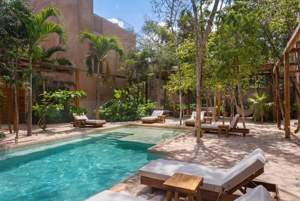 a pool in a courtyard with chairs and tables at 3BR Home in Gated Community with Private Rooftop Plunge Pool, Grill & Shared Pool in Tulum