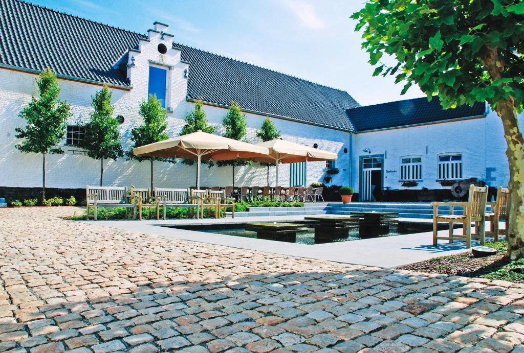 a patio with tables and umbrellas in front of a building at Hotel Aulnenhof in Landen