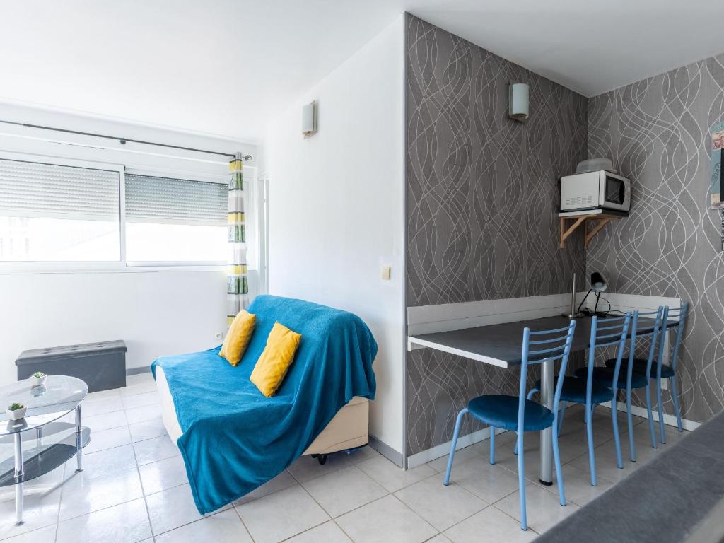 Ce petit appartement dispose d'un canapé bleu et d'une table. dans l'établissement Appartement au Coeur de Mimizan Plage pour 4 Personnes, à Proximité des Commerces et Plages - FR-1-50-142, à Mimizan