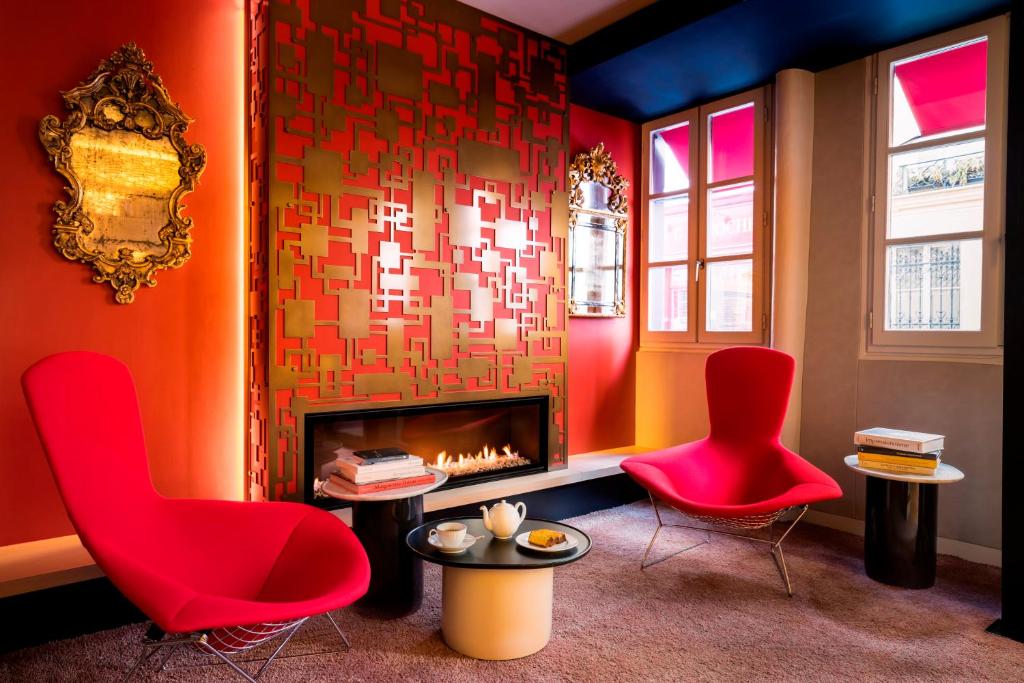 a living room with two red chairs and a fireplace at Hôtel de Lille - Saint-Germain des Près in Paris