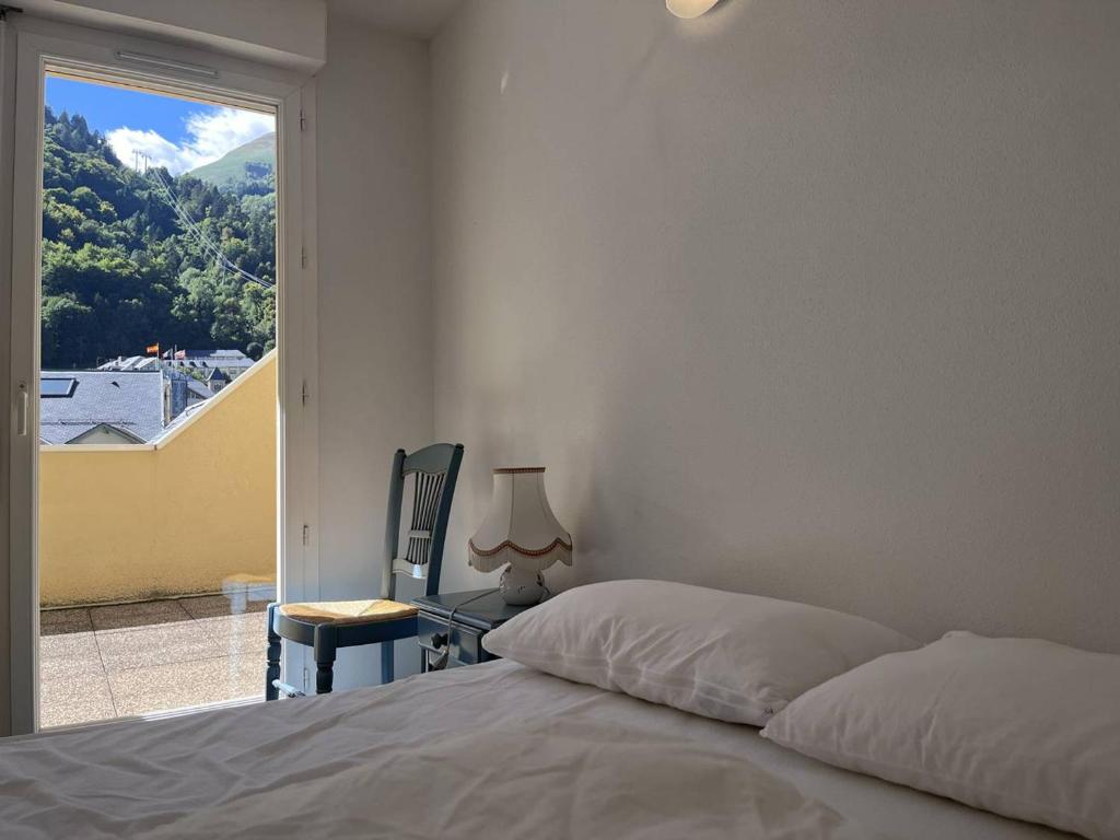 une chambre avec un lit, une chaise et une fenêtre dans l'établissement Appartement lumineux T2 à Cauterets, balcon, parking proche, 4 pers. - FR-1-812-42, à Cauterets