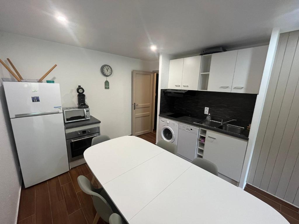 Il comprend une cuisine équipée d'une table blanche et d'un réfrigérateur blanc. dans l'établissement Châtel : Appart 6 pers, Parking, Accès WIFI - FR-1-198-267, à Châtel