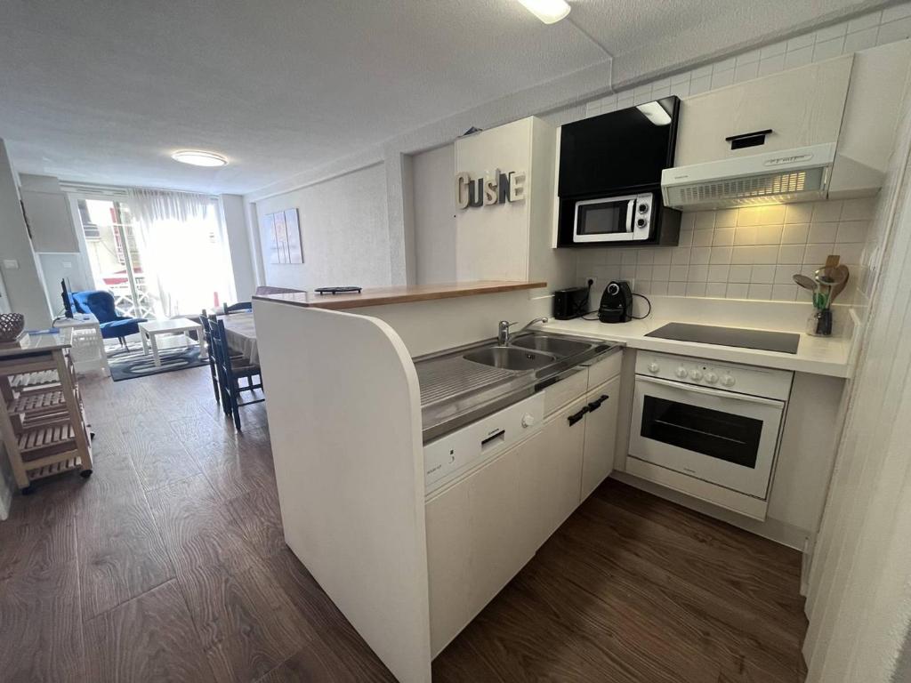 une cuisine avec un évier et une cuisinière four supérieur dans l'établissement Confort moderne à Cauterets : T2 avec cuisine équipée et alcôve. Capacité 4 pers. - FR-1-812-57, à Cauterets