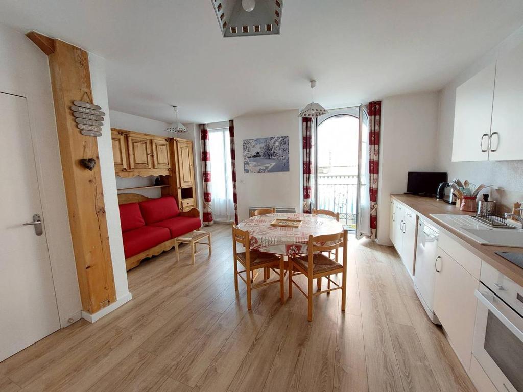 Il comprend une cuisine et un salon avec une table et un canapé rouge. dans l'établissement Charmant studio à Cauterets avec balcon et couchages pour 4 personnes - FR-1-812-62, à Cauterets