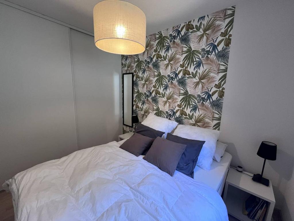 une chambre avec un lit blanc avec des oreillers bleus dans l'établissement Appartement à Cauterets avec balcon et parking privé - FR-1-812-96, à Cauterets