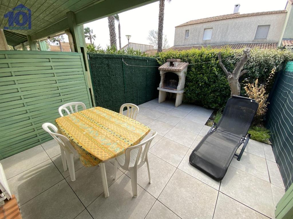 une terrasse avec une table, des chaises et une cuisinière dans l'établissement Pavillon 5 pers avec piscine et parking à Valras-Plage - FR-1-781-60, à Valras-Plage
