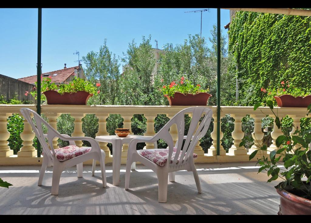 - deux chaises et une table sur une terrasse couverte avec une clôture dans l'établissement Hôtel Select, à Salon-de-Provence