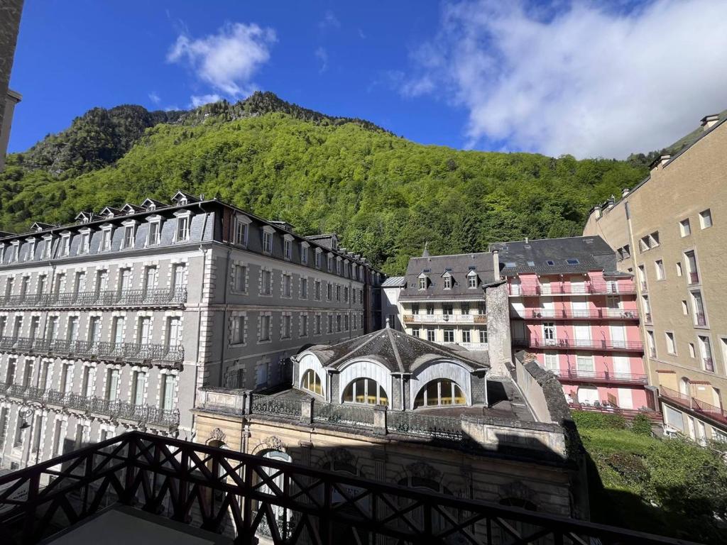 un groupe de bâtiments avec une montagne en arrière-plan dans l'établissement Appartement lumineux avec balcon au centre de Cauterets - FR-1-812-121, à Cauterets