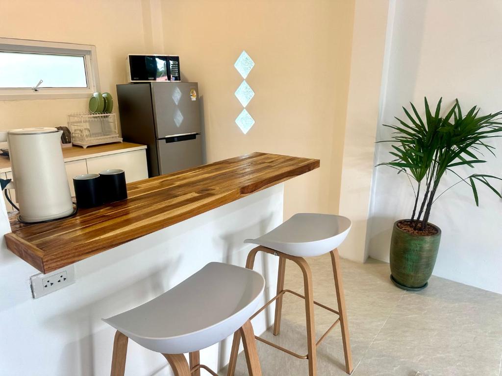 a kitchen with a counter with two stools and a refrigerator at lala bungalow in Ban Tai