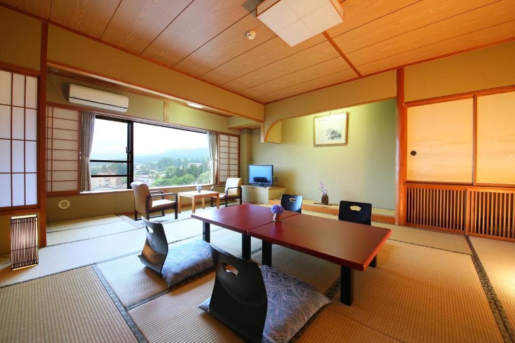 Habitación con mesa, sillas y ventana grande. en Hotel Taiko, en Myoko