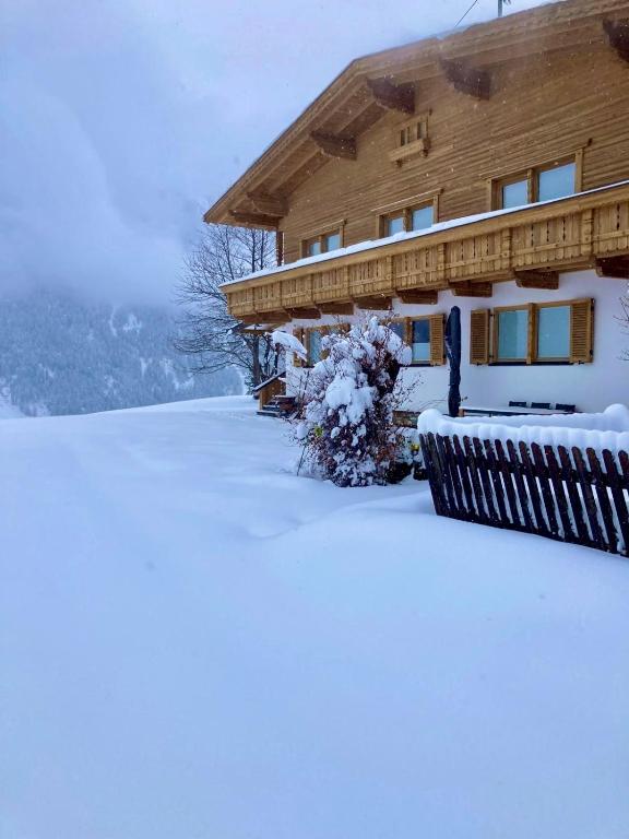 a house covered in snow in front of it at Chalet Heimatjuwel in Längenfeld