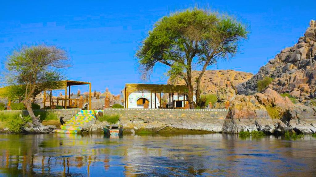 un edificio sul lato di un fiume con alberi di ASSINGAR camp a Jazīrat Suhayl