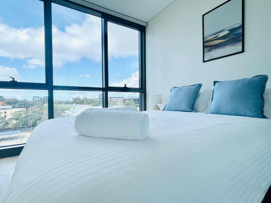 a white bed in a room with a large window at Modern stylish 3 bedroom condo - Parking, Gym, Pool in Sydney