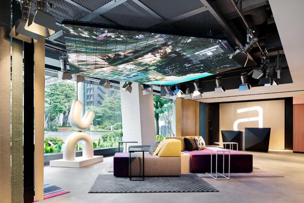 a room with a bed and a couch and a table at Aloft Tokyo Ginza in Tokyo