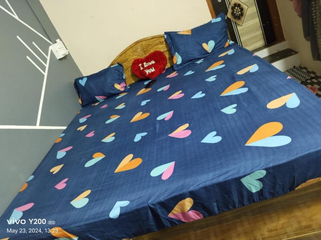 a bed with a blue comforter with lots of colorful leaves at Family Fun DELUXE VILLA 1 in Talguppa
