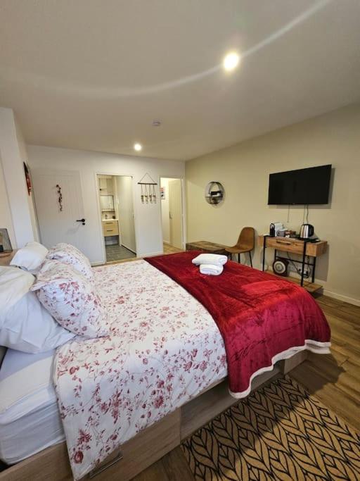 une chambre avec un grand lit avec une couverture rouge dans l'établissement Chambre d'hôte Aphrodite, à Sainte-Geneviève-des-Bois