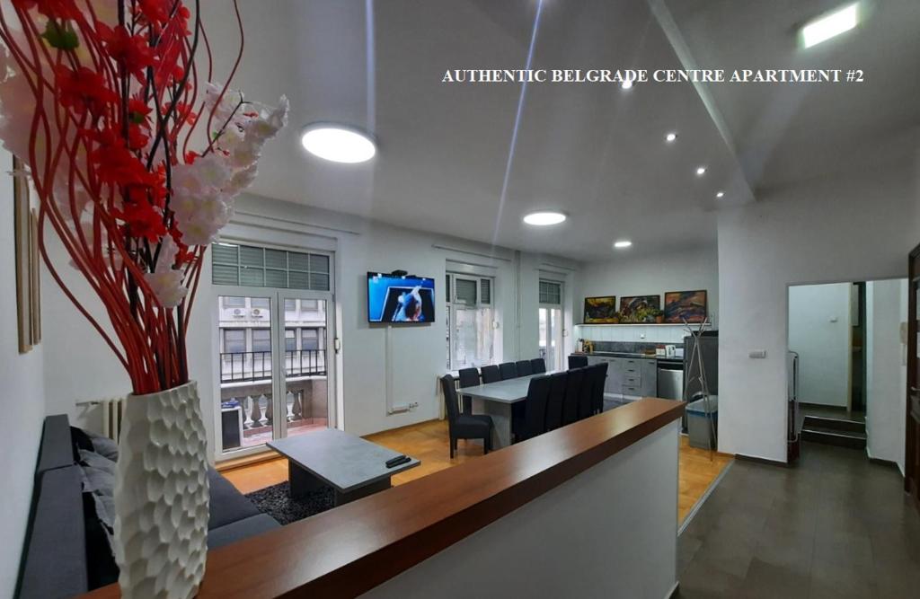 Authentic Belgrade Centre - New Year 2026 - Suites and large Apartments for Groups - Up to 63 Guests in one Building في بلغراد: غرفة معيشة مع طاولة وكراسي ومزهرية مع الزهور