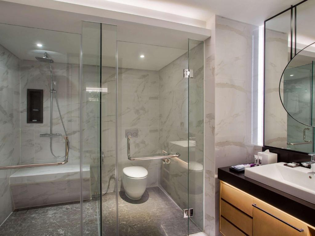 a bathroom with a shower and a toilet and a sink at Mercure Jakarta Batavia in Jakarta