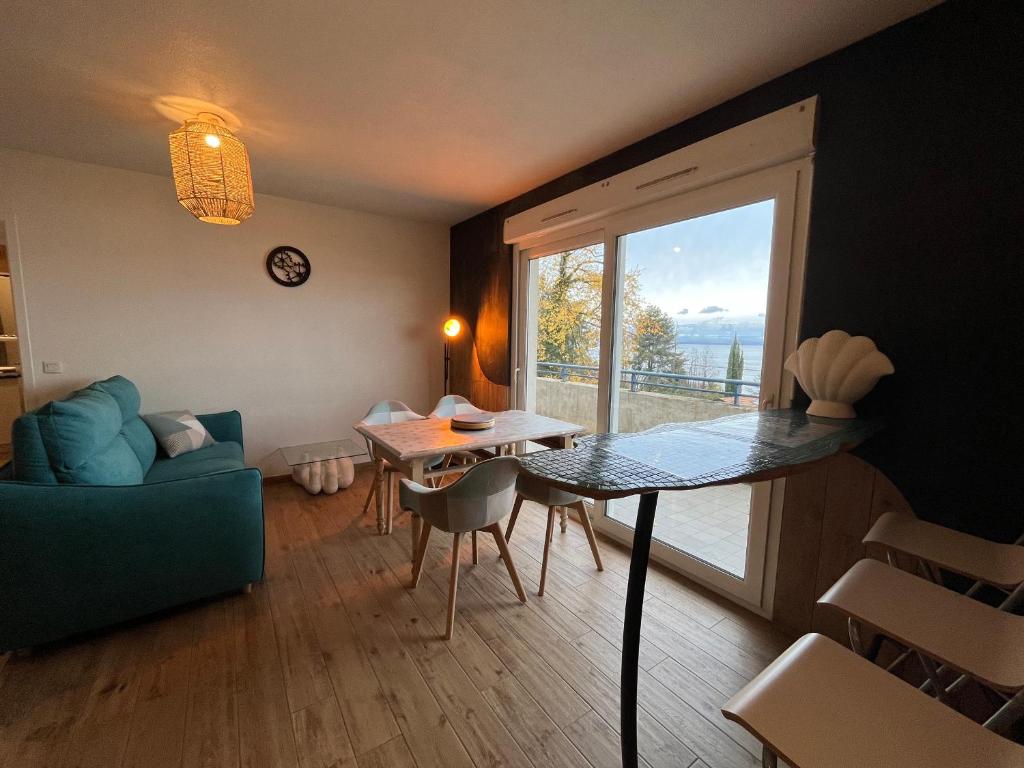 a living room with a table and a large window at Appartement lumineux avec piscine et parking à Évian - FR-1-498-109 in Évian-les-Bains
