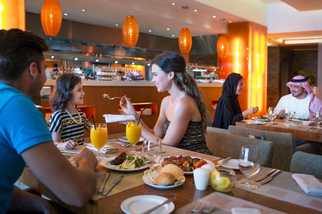 a group of people sitting at a table in a restaurant at Yas Island Rotana Abu Dhabi in Abu Dhabi