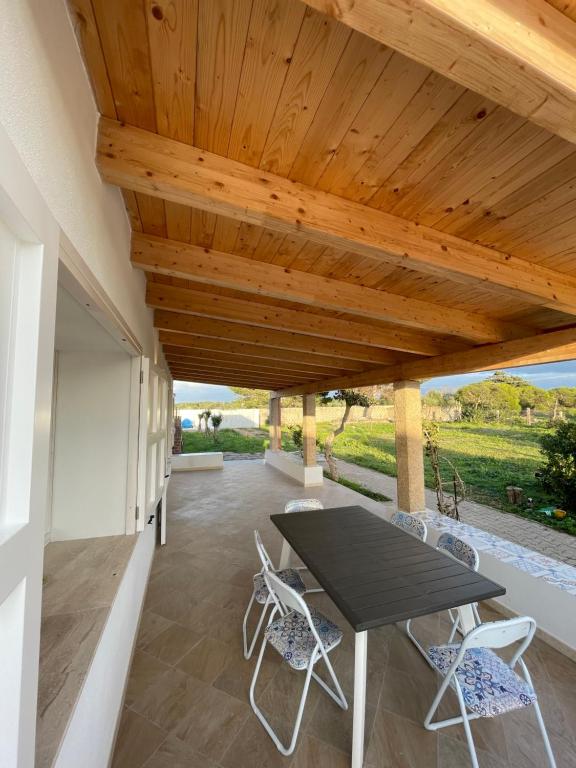 a patio with a table and chairs under a wooden ceiling at Villa Nido dei Passeri in Calasetta