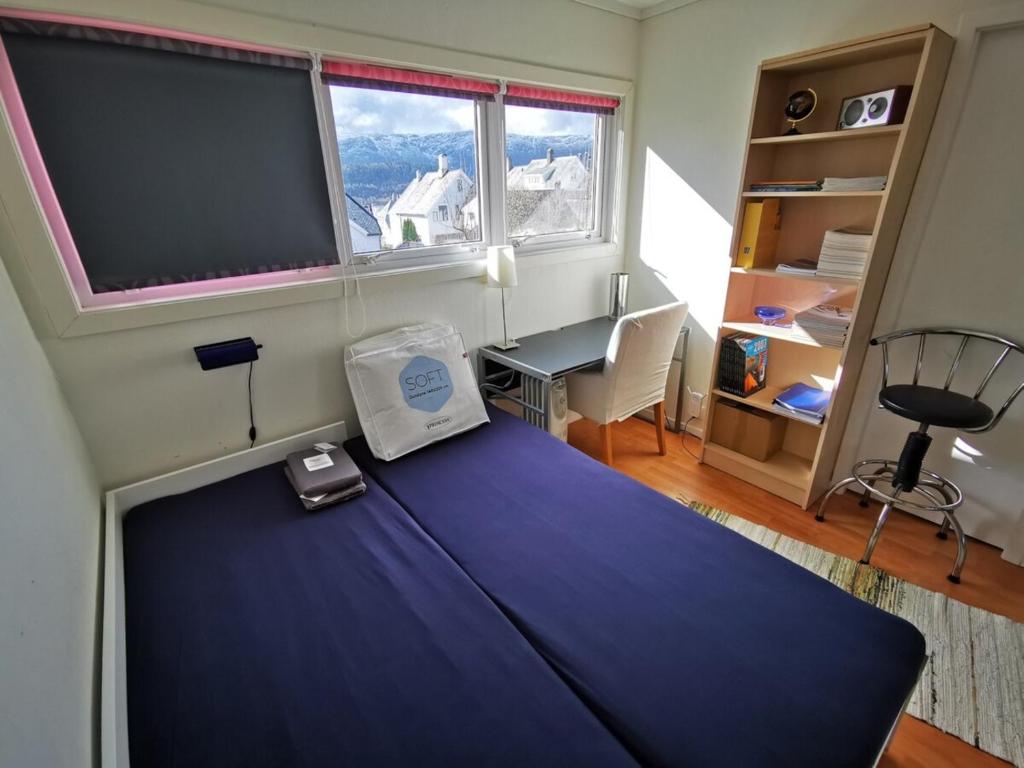 a bedroom with a bed with a large window and a desk at Private room in central homestay apartment with sea view in Ålesund
