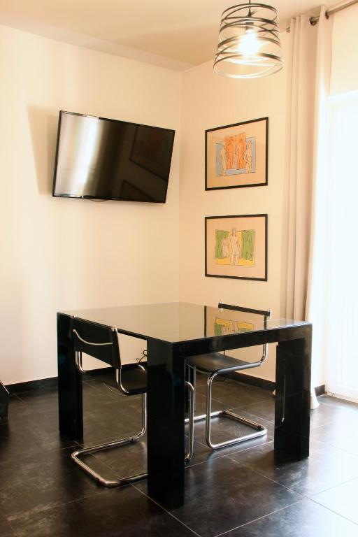 a black dining room table with chairs and a flat screen tv at B&B Il Vicoletto - Vitulazio in Vitulazio